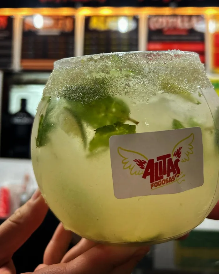 Bebida de limón con hierbabuena en copa con el logo de Alitas Fogosas