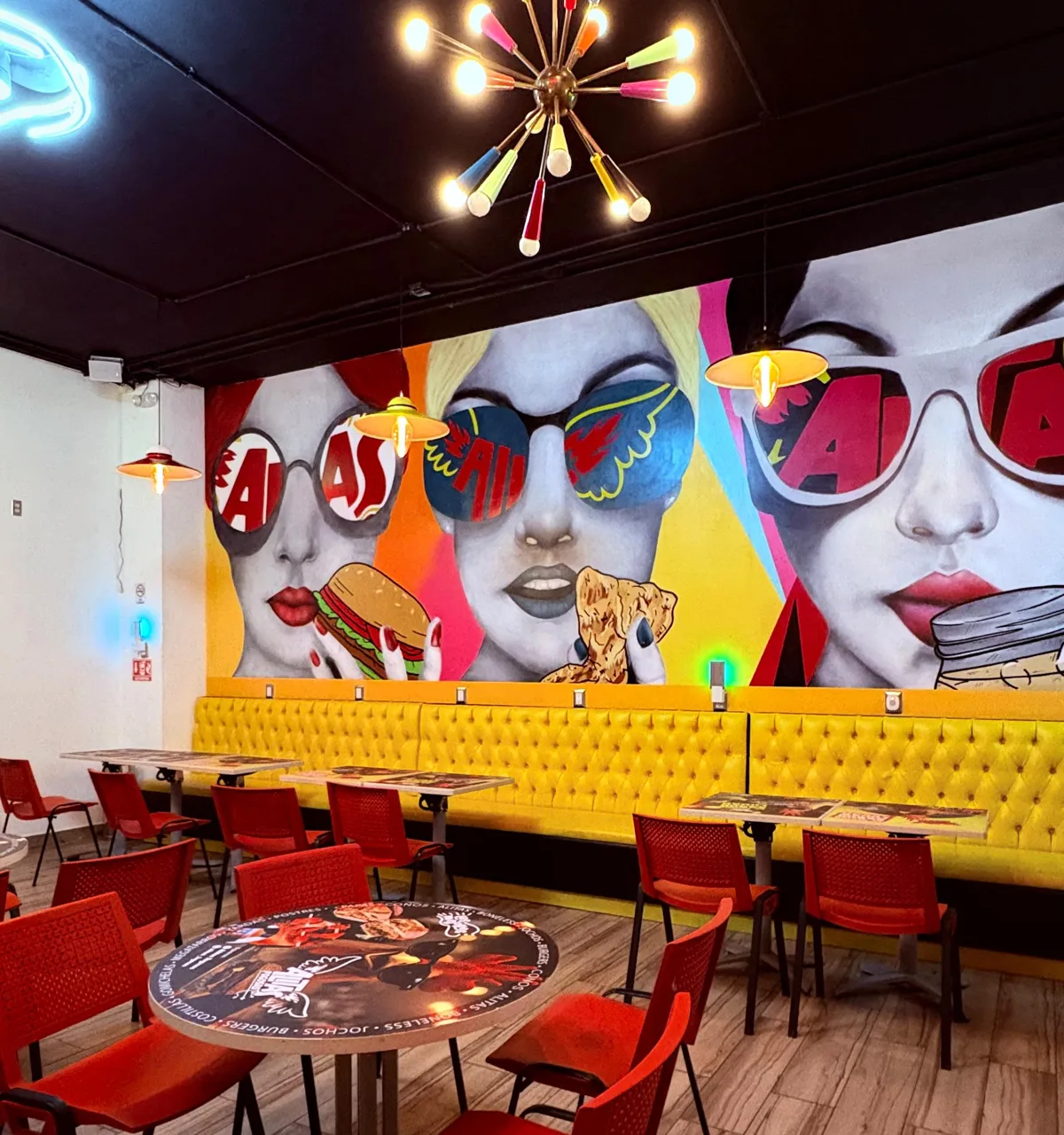 Interior con murales de colores, sillones amarillos y sillas rojas